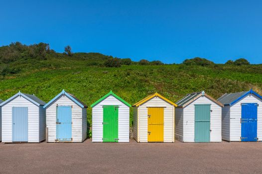 Colourful beach houses. Row of multicolored beach huts against blue sky.