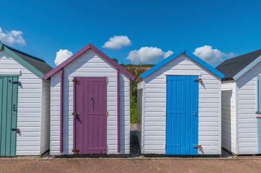 Colourful beach houses. Row of multicolored beach huts against blue sky.