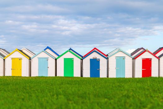 Colourful beach houses. Row of multicolored beach huts against blue sky.