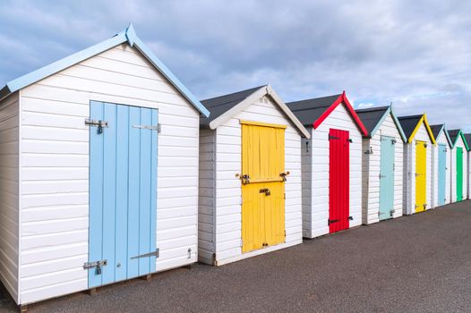 Colourful beach houses. Row of multicolored beach huts against blue sky.