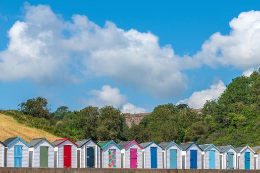 Colourful beach houses. Row of multicolored beach huts against blue sky.