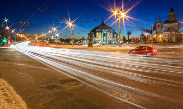 Winter night in Tula, Russia. Long exposure shot with traffic light trails. Arms museum and church background.