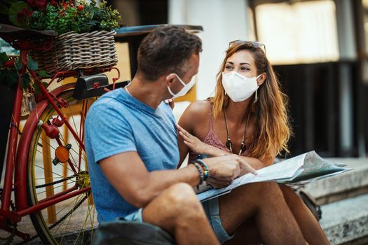 Shot of a happy couple with protective N95 mask spending time on vacation and exploring a Mediterranean city at corona pandemic. 