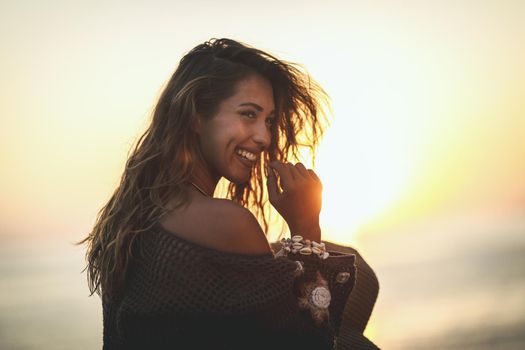 A beautiful young woman is embarrassed and relaxing on the beach at the sunset. 