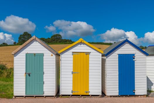 Colourful beach houses. Row of multicolored beach huts against blue sky.