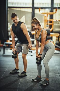 Shot of an attractive young woman working out with personal trainer at the gym.