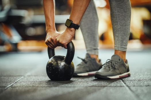 Cropped shot of a unrecognizable female athlete working out with kettlebell at the gym.