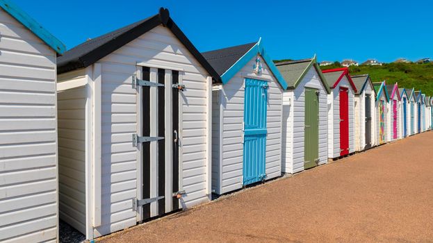 Colourful beach houses. Row of multicolored beach huts against blue sky.