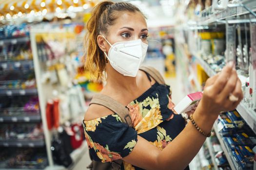 Shot of a young woman is wearing N95 protective mask while buying in supermarket during Covid-19 pandemic.