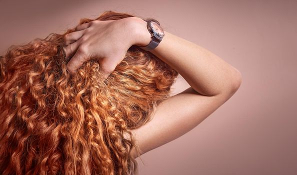Woman's hand smoothes long Curly Red Hair. Wavy Hair Extensions Concept.