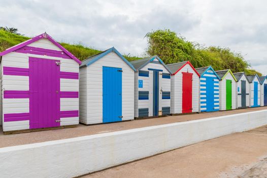 Colourful beach houses. Row of multicolored beach huts against blue sky.