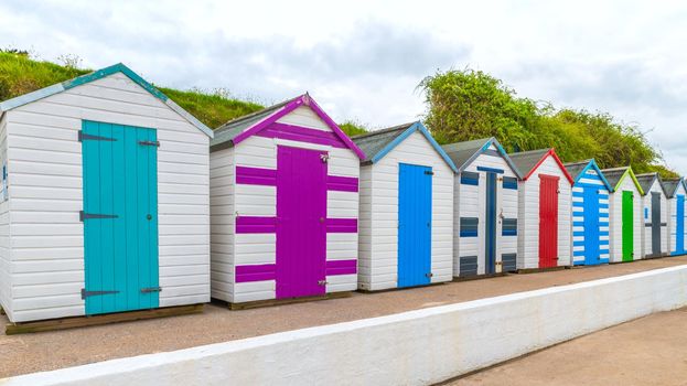 Colourful beach houses. Row of multicolored beach huts against blue sky.