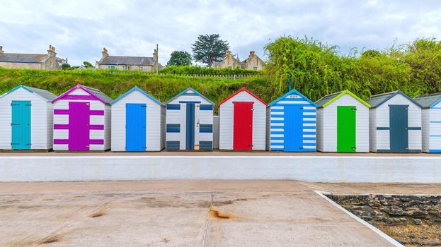 Colourful beach houses. Row of multicolored beach huts against blue sky.