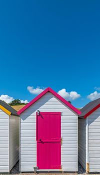 Colourful beach houses. Row of multicolored beach huts against blue sky.