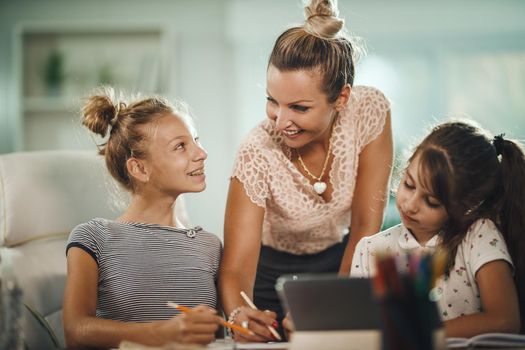 Shot of a beautiful young mother helping hers two daughters with homework during COVID-19 pandemic.