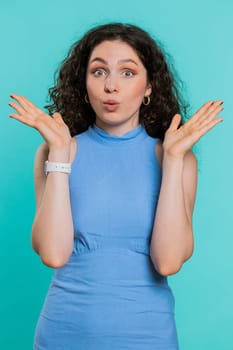 Oh my God, Wow. Excited amazed winner woman raising hands in surprise looking at camera with big eyes, shocked by sudden victory. Sincere attractive girl isolated on blue studio background. Vertical