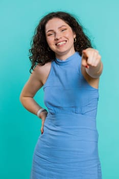 Amused lovely woman pointing finger to camera, laughing out loud, taunting making fun of ridiculous appearance, funny joke anecdote. Brunette girl isolated alone on blue studio background. Vertical