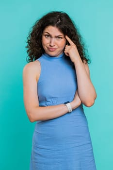 You are crazy, out of mind. Displeased woman pointing at camera, show stupid gesture finger near head, blaming some idiot for dumb insane plan idea, senseless talk. Girl on blue background. Vertical