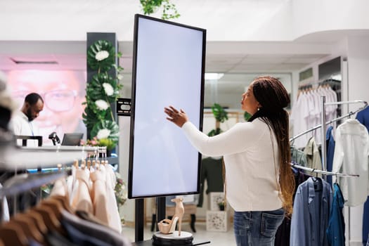 African american woman using smart display board to shop for shoes in fashion boutique. Customer checking stiletto new collection information on advertisement blank whiteboard