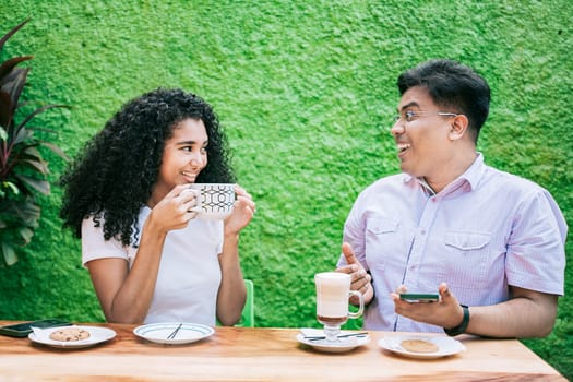 Two happy friends having a coffee and talking. Man and woman talking and enjoying a coffee in a cafeteria
