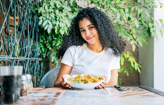 Portrait of smiling girl eating caesar salad. Concept of healthy food and healthy life, Beautiful girl sitting holding a caesar salad
