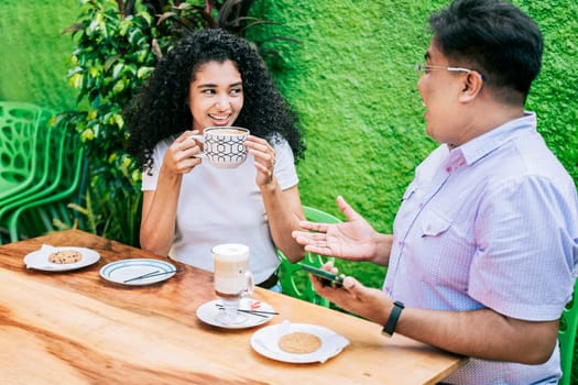 Smiling friends talking and enjoying coffee at a table. Concept of friends enjoying a good coffee. Two happy friends having a coffee and talking