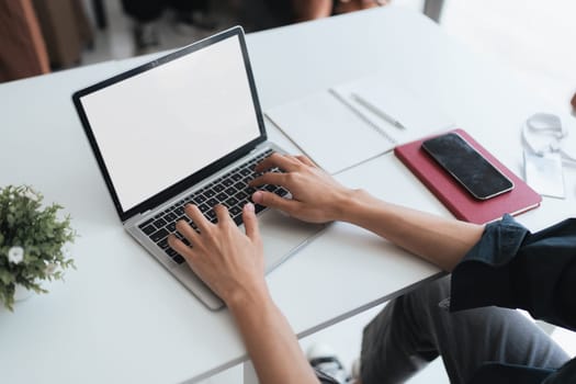 blank screen of man hand working on laptop computer and peper work while sitting at the table, mockup blank screen for product display or graphic design.