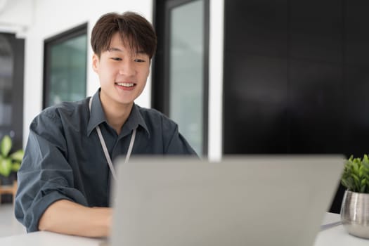 Young business man working at office with laptop and papers on desk.