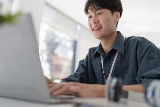 Young business man working at office with laptop and papers on desk.