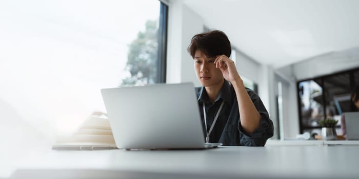 Businessman stressed with work and deadlines Stressed businessman with laptop sitting at desk in office.