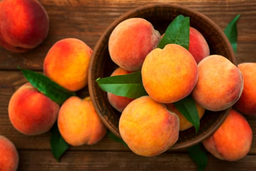 Ripe and tasty and juicy peaches lie on a plate on a wooden table. Large peaches on rustic wooden background, selective focus.
