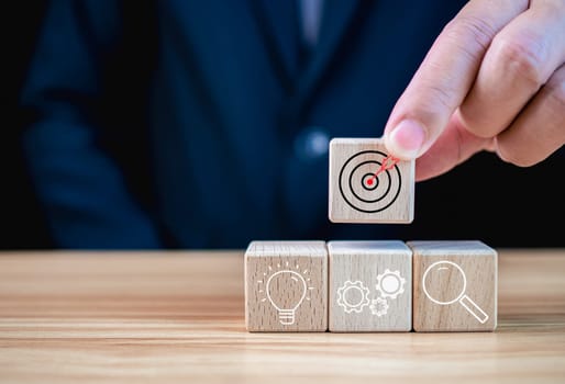 Businessman holding a wooden block that prints target icon. Business concept. Management concept. Business planning concept.