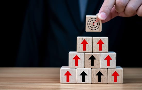 Businessman hand holding a wooden block which prints a target icon. Business goals and objectives concept. business competition