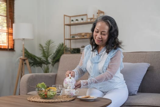 Senior Asian woman eatfresh and clean vegetarian salad with tea at home. Health care concept.