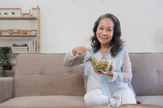 Senior Asian woman eating fresh and clean vegetarian salad at home. Health care concept.