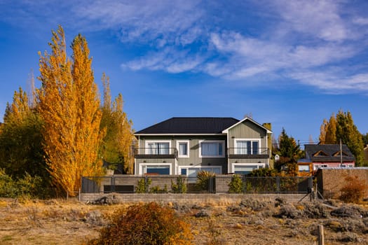 A typical corrugated iron clad house with autumnal trees in southern Argentina, Patagonia, South America