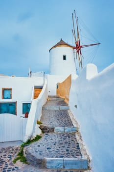 Old traditional whitewashed greek windmill on Santorini island in Oia town with stairs in street. Oia village, Santorini, Greece