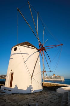 Scenic view of famous Mykonos town windmills. Traditional greek windmills on Mykonos island at sunrise with cruise ship in background, Cyclades, Greece