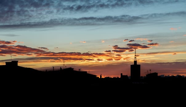 Horizontal shot of clouds floating across the sky with the setting sun on a spring evening over urban space. Concept of summer cityscapes. Copyspace.