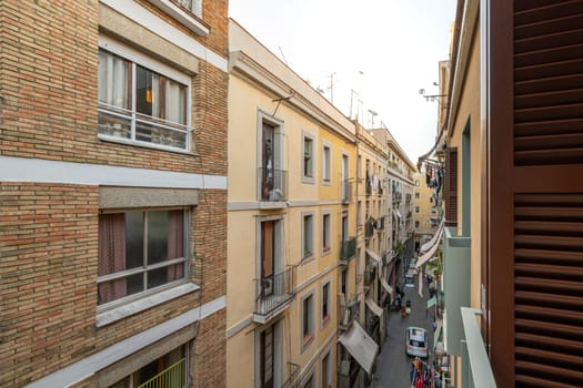 View from the balcony to a narrow Barcelona street among modern brick houses with large windows. The concept of modern European architecture.