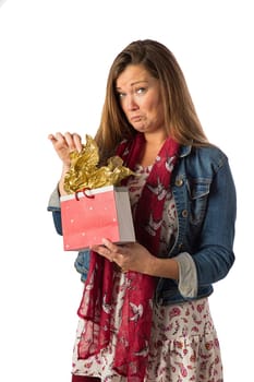 Forty year old woman, wearing bohemian style clothing, opening a gift bag, with unhappy expression, isolated on a white background
