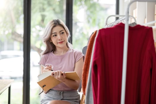 Female entrepreneur writes on parcel box after reading address on notebook. Online seller concept.