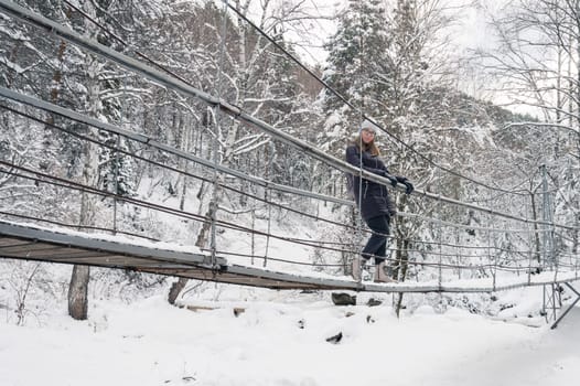 Woman in winter jacket walking in snowy winter forest, snowy winter day