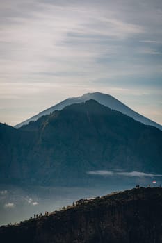 Mountain Batur landscape view in foggy morning. Volcano Batur silhouette with misty and cloudy sky