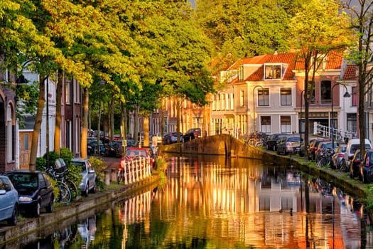 Delt canal with old houses and cars parked along on sunset. Delft, Netherlands