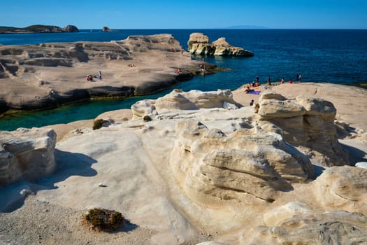 White rocks of famous tourist attraction of Milos island Sarakiniko beach with tourist relax and Aegean sea, Milos island , Greece