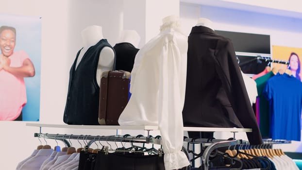 Shopping mall boutique filled with fashion tailoring, multiple racks with fashionable formal wear. Empty clothing showroom with trendy shirts on hangers, small business concept.