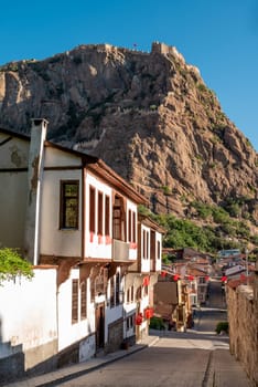 Traditional Turkish Ottoman houses in Afyonkarahisar Turkey. Afyon Castle on the rock and Mevlevihane Museum in front of it