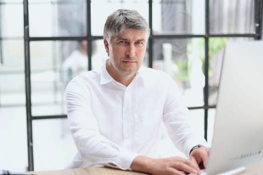 Businessman in shirt working on his laptop in an office.