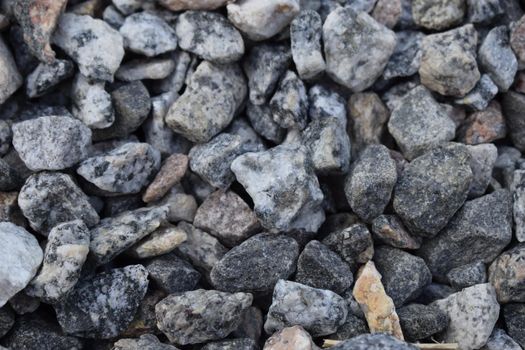 Gravel Rock Texture. Crushed stone and gravel on the ground. Texture background brown stones on a black earth background. Image of broken stones and gravel